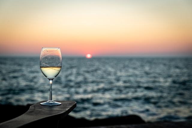blue-wave-cruises-calypso-sunset-sip A guest enjoying a chilled drink on the deck of Calypso during a golden sunset over Mykonos and Little Venice.