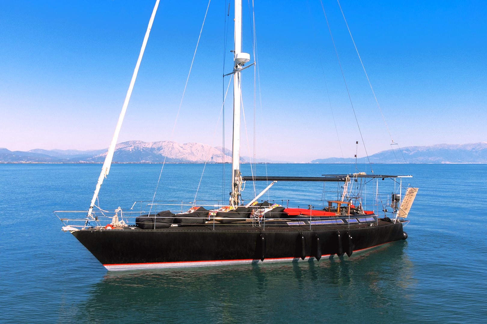 Calypso motor yacht cruising in Mykonos, luxury boat tour to Delos and Rhenia islands with sunbeds and bean bags.